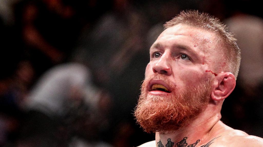 Conor McGregor, battered and bloody, looks on after being defeated by Nate Diaz.