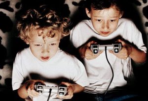 two kids playing playstation one in the dark