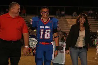 Collin Saring stands smiling with his parents on Senior Night in high school.