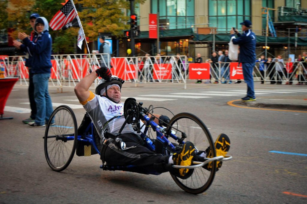 A handcyle racer pumps his fist as he passes the roaring crowd at the Chicago Marathon